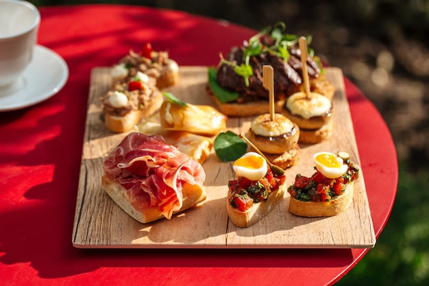 Assortiment de tapas espagnoles avec différentes garnitures sur la planche de bois