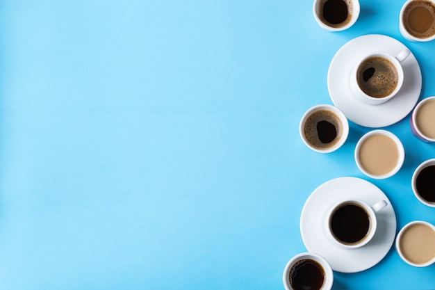 Assortiment de tasses à café et mugs avec torréfaction noire, americano, cappuccino, lait sur fond bleu. Mise à plat de l'espace de copie à la mode créatif