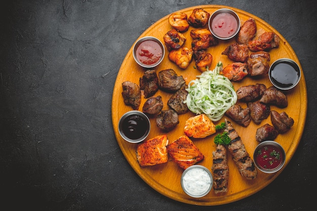 Assortiment de viandes grillées et de sauces sur une table en bois.