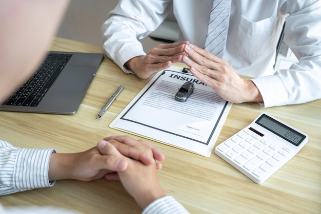 Assurance et protection des soins de l'agent immobilier d'homme d'affaires de concept de voiture avec geste de protection du petit modèle de voiture à la main