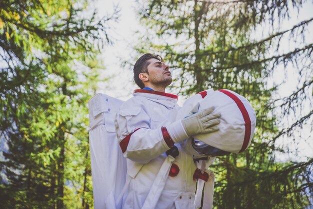 Photo un astronaute détourne le regard alors qu'il se tient dans la forêt