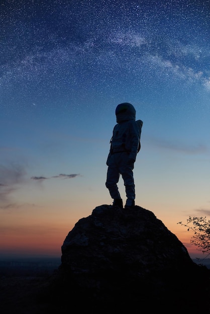 Astronaute se tenant sous le beau ciel nocturne avec des étoiles