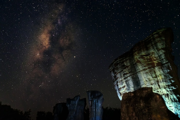 Photo astroscape la nuit avec des rochers au premier plan