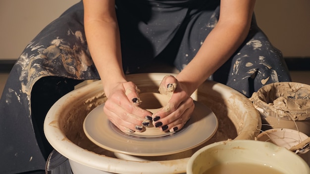 Atelier de céramique - la jeune fille fabrique un pot d'argile sur un tour de potier. gros plan des mains