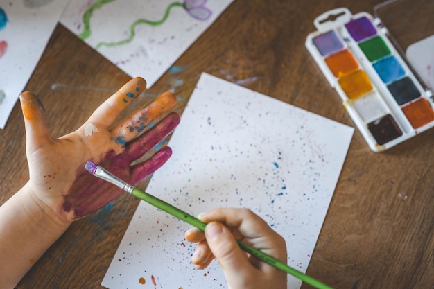 Photo atelier de dessin pour enfants enfants heureux font des empreintes de main avec de la peinture