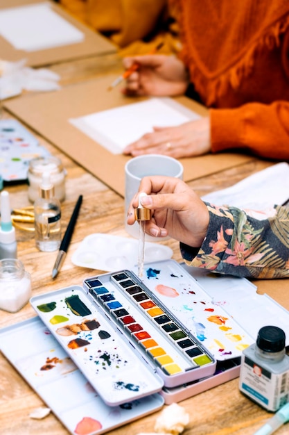 Atelier de peinture à l'aquarelle Gros plan d'une main de fille versant de l'eau avec une pipette