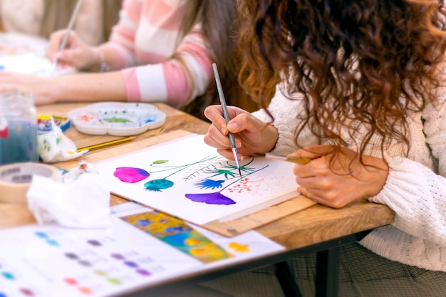 Atelier de peinture à l'aquarelle Jeune femme dessinant à l'aquarelle à table à l'intérieur gros plan