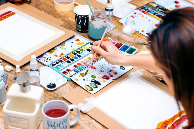 Atelier de peinture à l'aquarelle Jeune femme mélangeant les couleurs avec un pinceau