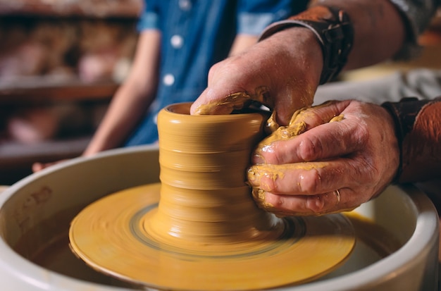 Atelier de poterie. Grand-père enseigne la poterie à sa petite-fille. Modelage d'argile