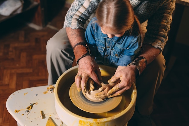 Atelier de poterie. Grand-père enseigne la poterie à sa petite-fille. Modelage d'argile