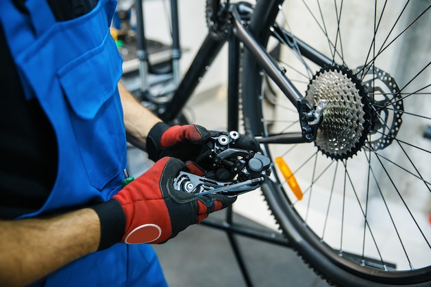 Atelier de réparation de vélos, l'homme règle le commutateur de vitesse