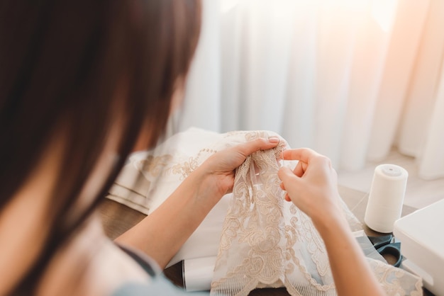 Atelier ou tailleur coud des rideaux gros plan de mains féminines dans lesquelles il y a une aiguille