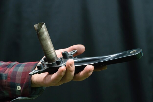 Ateliers de réparation de vélos Pièces de rechange de mauvaise qualité Entre les mains d'un mécanicien une pièce cassée Cassé l'axe du boîtier de pédalier