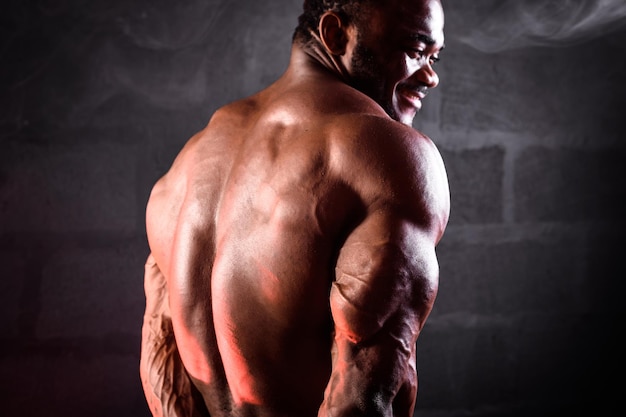 L'athlète africain de bodybuilder démontre les triceps et les muscles du dos