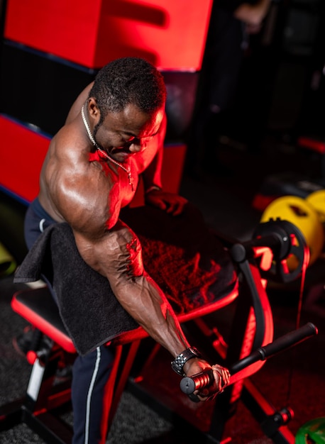 Athlète afro-américain avec un corps solide faisant du travail en poussant des exercices dans la salle de gym Vue de côté Fond clair sombre