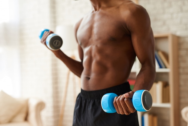 Athlète afro-américain pompant des muscles par des haltères