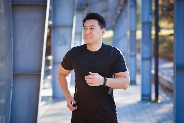 Athlète asiatique sur un jogging matinal près du stade, homme d'affaires prospère est engagé dans la forme physique le matin avant le travail