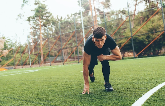 Athlète en bonne santé courant sur l'herbe verte dans le parc Coureur masculin en bonne santé sprintant à l'extérieur Jeune coureur masculin commençant son sprint sur le terrain de sport Mode de vie sportif et concept de personnes