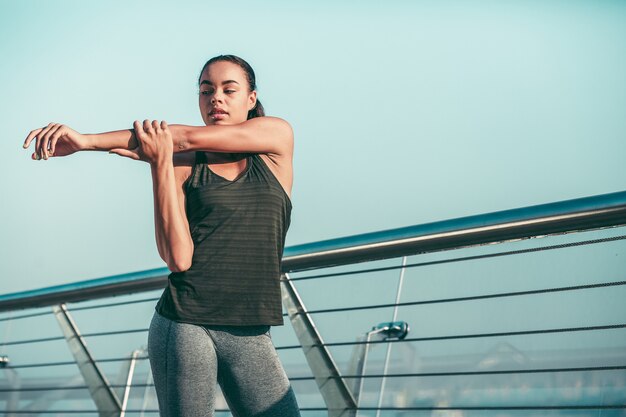 Athlète calme debout à côté de la rampe et réchauffant ses muscles