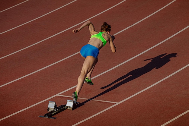 Une athlète commence à courir 400 mètres dans le stade