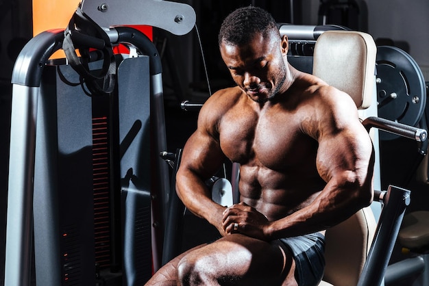 L'athlète dans la salle de gym assis dans le simulateur intégré pour les muscles de la poitrine