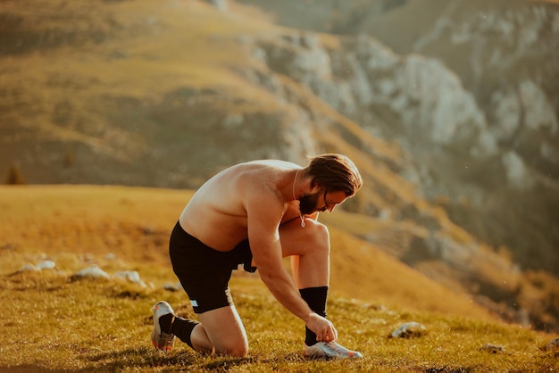 Un athlète déterminé se préparant au début de l'entraînement au sommet de la montagne au lever du soleil.