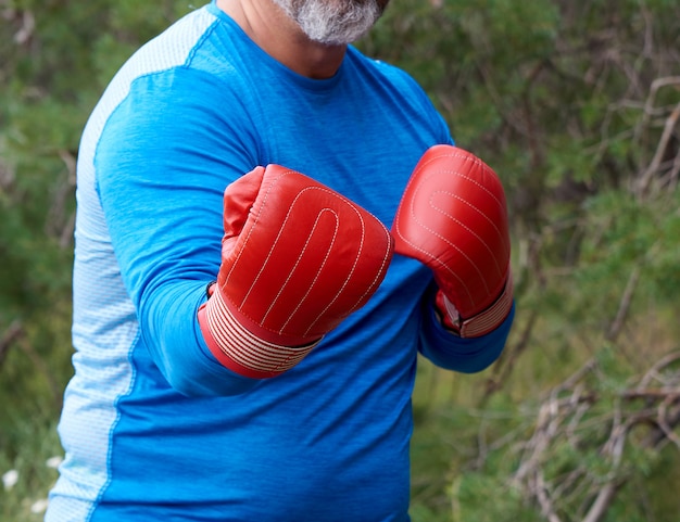 Athlète dodu adulte en gants de boxe en cuir rouge et uniforme bleu