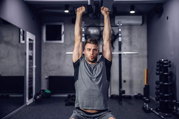 L'athlète entraîne des haltères dans la salle de gym sur un fond gris foncé