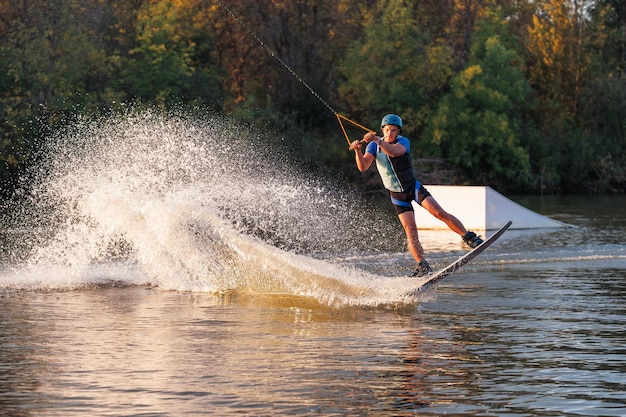 Un athlète exécute un tour sur le parc aquatique au coucher du soleil. Wakeboard rider