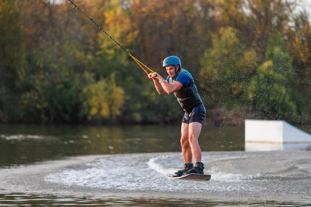 Un athlète exécute un tour sur le parc aquatique au coucher du soleil. Wakeboard rider