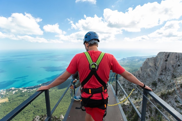 Un athlète extrême traverse le pont jusqu'à la falaise Saut à la corde