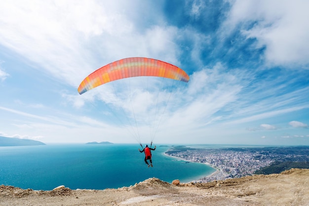 Athlète faisant du parapente sur fond de ciel nuageux au-dessus des montagnes un jour d'été