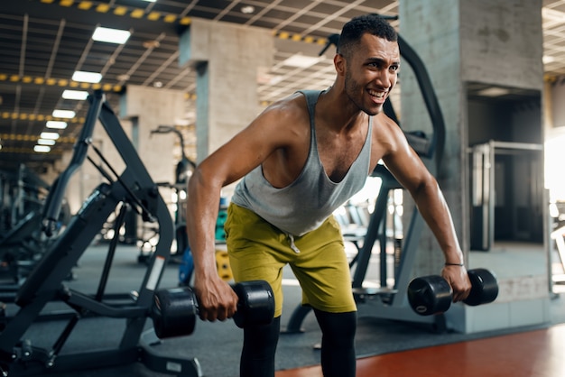 Athlète faisant de l'exercice avec des haltères dans une salle de sport