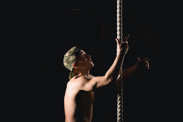 Athlète faisant de l'exercice de montée de corde de remise en forme dans la salle de gym