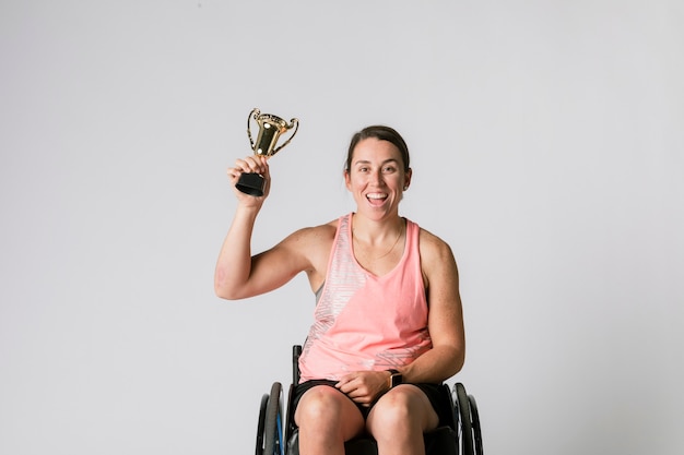 Athlète en fauteuil roulant tenant un trophée