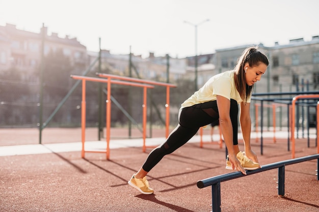 Athlète féminine active s'échauffant au terrain de sport