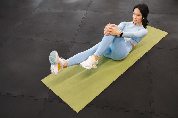Athlète féminine faisant des abdos exerçant des redressements assis sur le tapis de yoga