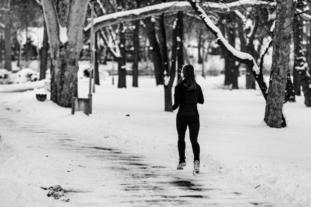 Athlète féminine faisant du jogging dans le parc le jour d'hiver dans le parc