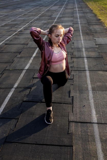 Athlète féminine préparant les jambes pour l'entraînement cardio Coureur de fitness faisant une routine d'échauffement Coureur de femme échauffant une athlète en plein air qui s'étire et s'échauffe sur une piste de course dans un stade