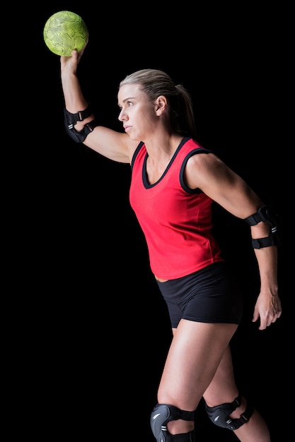 Athlète féminine avec protège-coude jetant le handball sur fond noir
