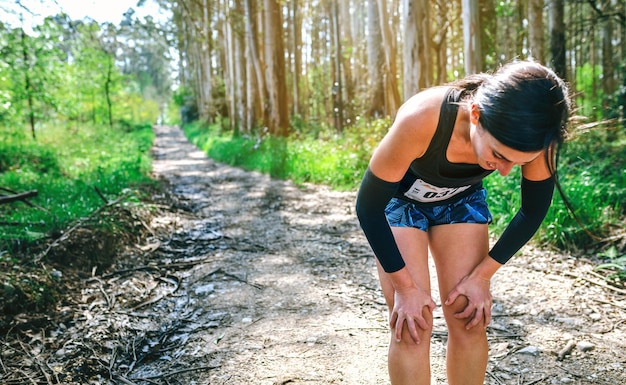 Athlète féminine s'arrêtant lors d'une compétition de trail