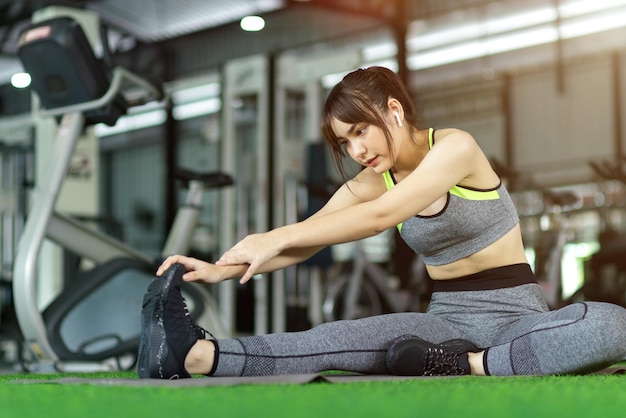 Athlète féminine séduisante faisant des exercices d'étirement de remise en forme avant l'entraînement au gymnase. Notion de sport