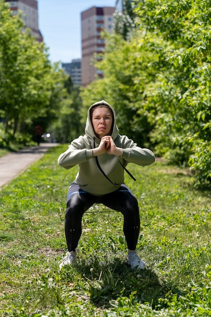 Photo athlète fille faisant du fitness dans un pays accroupi avec une bande élastique de remise en forme sur ses jambes