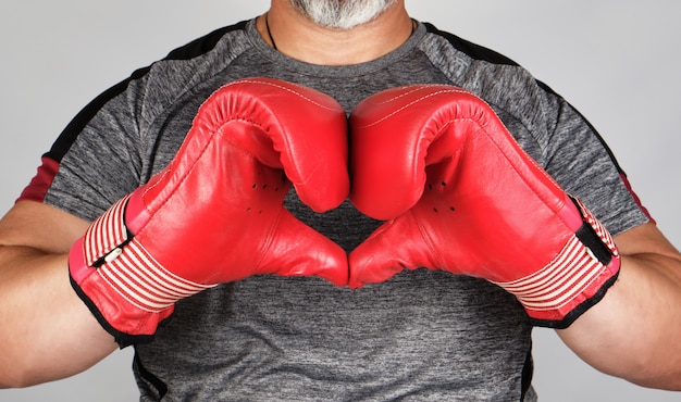 Athlète en gants de cuir de boxe rouge montre les mains avec un symbole de coeur