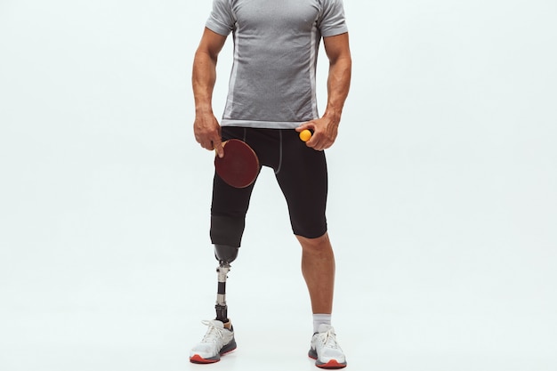 Athlète handicapé ou amputé isolé sur fond de studio blanc. Joueur de tennis de table masculin professionnel avec formation de prothèse de jambe en studio. Sport handicapé et concept de mode de vie sain.