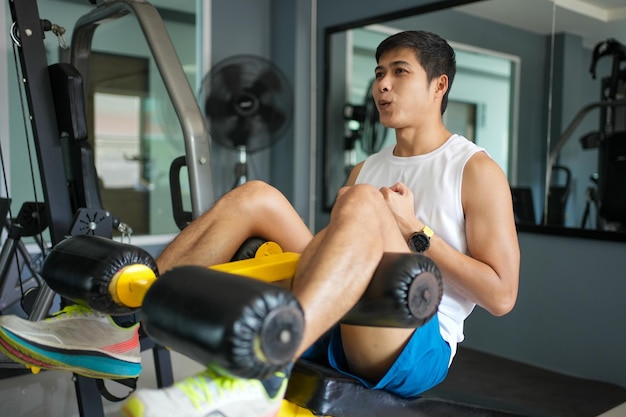 Athlète d'hommes asiatiques faisant des exercices de situps avec une machine pour renforcer les muscles pour les soins de santé au stade de gym