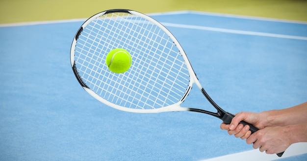 Athlète jouant au tennis avec une raquette contre l'image composite du terrain de tennis