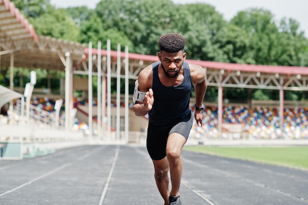 Athlète masculin afro-américain en vêtements de sport faisant la course seul sur une piste de course au stade