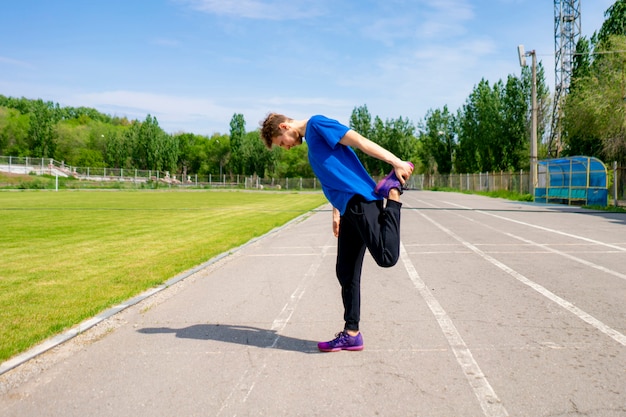 Athlète masculin concentré en plein air étirant son corps en vêtements de sport faisant des pratiques saines