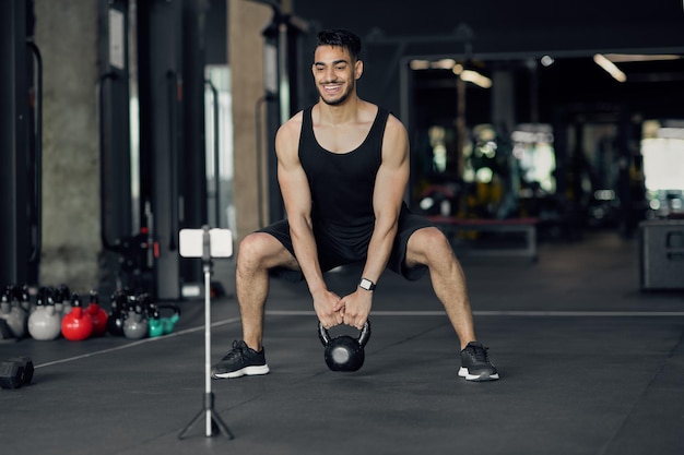 Athlète masculin du Moyen-Orient capturant des séances d'entraînement en ligne à la salle de sport pour un blog de fitness